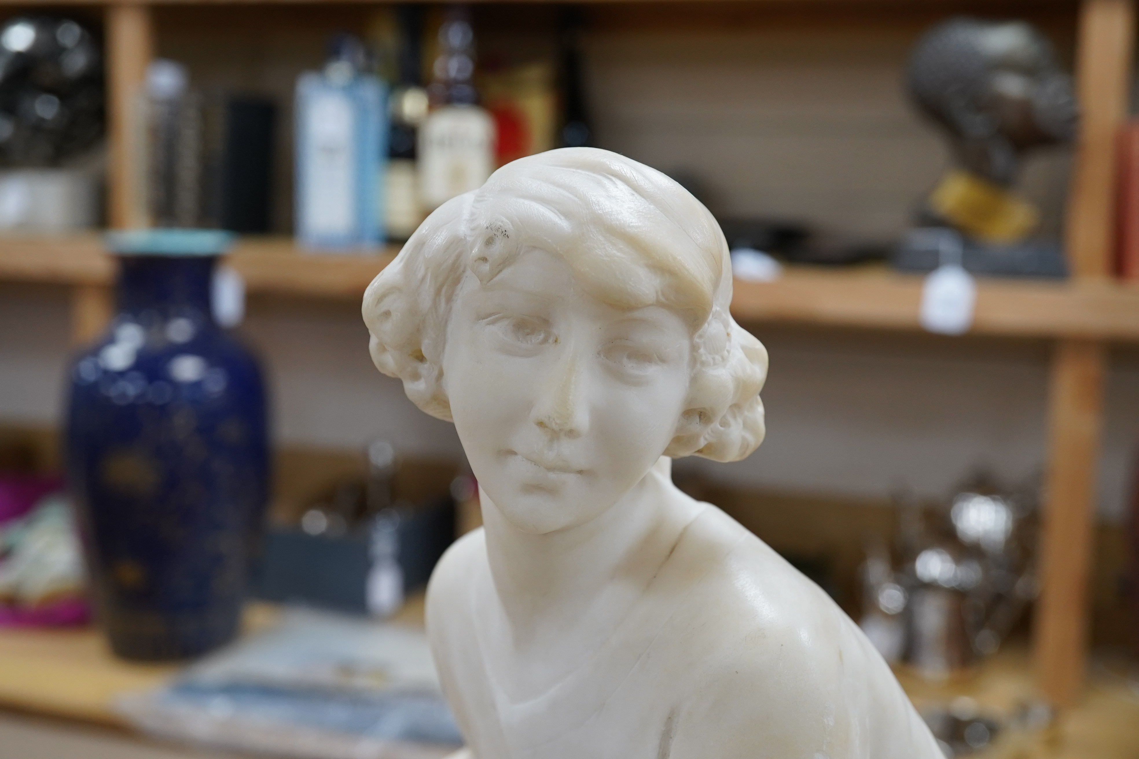 A French 1920’s-30’s alabaster sculpture of a lady seated on a stone wall, sculpture mounted on a marble stand, 63cm high. Condition - crack to alabaster at the front and discoloured restoration